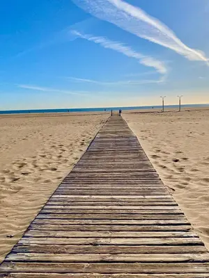 a wooden boardwalk stretches across a sandy beach at Charming fisherman's house Cabanyal Cabañal in Valencia