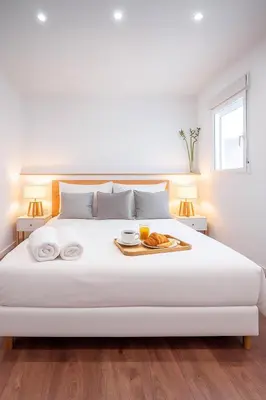a white bed with a tray of food on it at El Pilar Luxury Suites By VALENCIAFLATS EU in Valencia