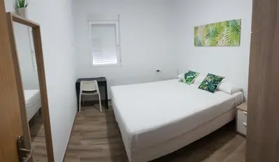 a white bedroom with a bed and a chair in it at Malva Arena in Valencia