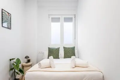 a white bedroom with a large white bed with green pillows at Balandra, Lovely flat close to center in Valencia