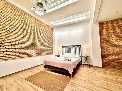 a bedroom with a bed and a brick wall at Mediterranean Apartament in Valencia