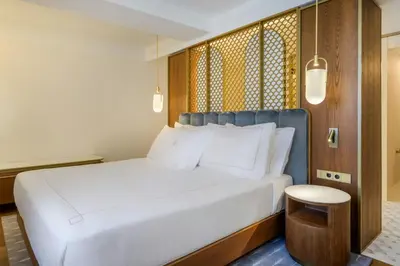 a bedroom with a bed and a living room at Grand Hotel Centenari, Valencia, Autograph Collection in Valencia