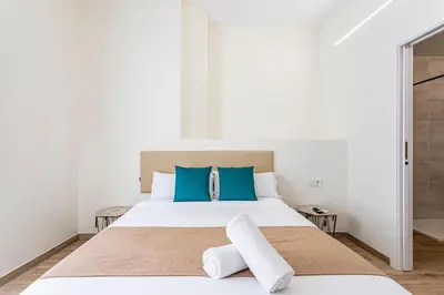 a white bedroom with a large bed with blue pillows at The Port Urban Loft in Valencia