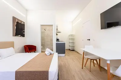 a white bedroom with a bed and a desk at The Port Urban Loft in Valencia