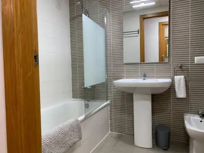 a bathroom with a sink and a mirror and a tub at Sunrise Beach Apartment Playa Puerto de Sagunto in Puerto de Sagunto