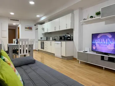 a living room with a television and a kitchen at Sunrise Beach Apartment Playa Puerto de Sagunto in Puerto de Sagunto