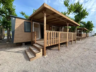 a wooden cabin with a porch and a staircase at Camping Los Naranjos in Moncófar