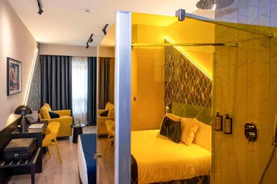 a bedroom with a yellow bed and a living room at Hotel Pathos by Mimood Aparthotels in Valencia