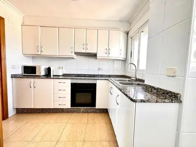 a white kitchen with white cabinets and a sink at Vistas al mar, El Puig in El Puig