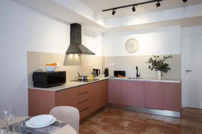 a kitchen with pink cabinets and a clock on the wall at SingularStays Palau de la Musica Lofts in Valencia
