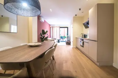 a dining room and kitchen with a wooden table and chairs at Apartamento moderno con terraza en el centro in Valencia