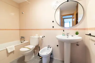 a bathroom with a toilet and a sink and a mirror at Global Vacacional, Planta baja en Canet de Berenguer in Canet de Berenguer