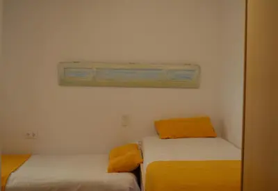 two beds with orange pillows in a room at Els Vents primera línea playa Puçol in Puzol