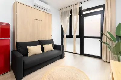 a living room with a black couch and a sliding door at Travel Habitat Nou Mestalla Suites in Valencia