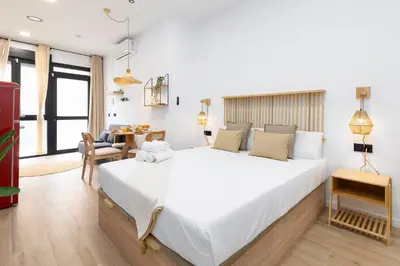 a bedroom with a large white bed and a table at Travel Habitat Nou Mestalla Suites in Valencia