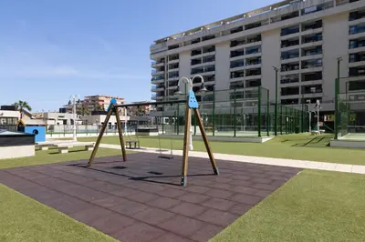 a playground with a swing set in a park at Apartamento con Vistas al mar, Piscina y Pista de Paddle in Valencia