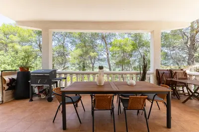 a porch with a table and chairs and a grill at Chalet Barraca d 'Aigües Vives in Barraca de Aguas Vivas