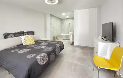 a bedroom with a bed and a tv and a yellow chair at Gorgeous Home In Llaurí With Wifi in Llaurí