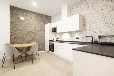 a kitchen with white cabinets and a table and chairs at Arm Suites by Concept Flats in Valencia