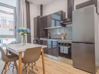 a kitchen with a table and a stainless steel refrigerator at Winahost Apartamento Benimaclet 1 in Valencia