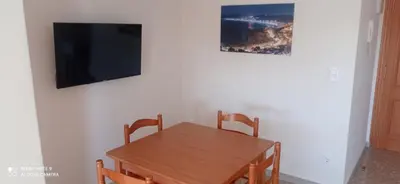 a dining room with a wooden table and a flat screen tv at Apartamento Cullera Playa in Cullera