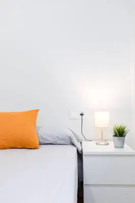 a white bed with an orange pillow and a nightstand at Beachside Apartment Valencia Ideal for Digital Nomads in Valencia