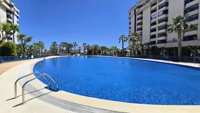 a large blue swimming pool with palm trees and buildings at BEACH VALENCIA LUXURY D15-21 Apartment with terrace and sea views with two rooms in Valencia