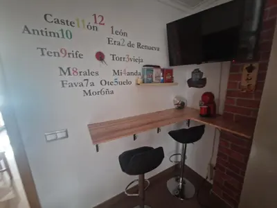 a room with a bar with two stools and a television at Calma mediterránea in Favareta