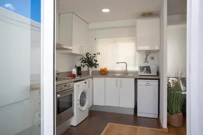 a kitchen with white cabinets and a washer and dryer at SingularStays Plaza Andújar in Valencia