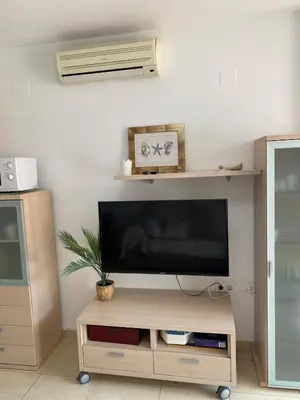 a flat screen tv sitting on top of a wooden tv stand at Encantador apartamento con terraza en la Playa de Moncófar in Moncófar