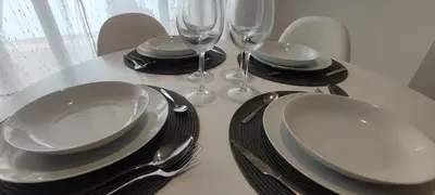 a table with white plates and silverware and wine glasses at Magnifico apartamento de playa in Moncófar