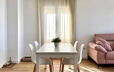 a white dining room table with white chairs and a couch at Beach Front Apartment In Sagunto in Sagunto