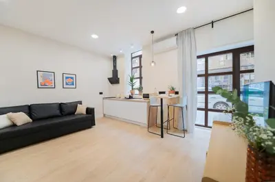 a living room with a black couch and a kitchen at Apartments LEON GABRIEL MIRÓ in Valencia