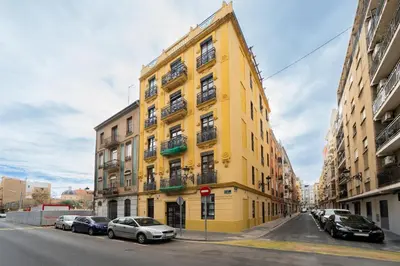 a yellow building on a street with parked cars at Apartments LEON GABRIEL MIRÓ in Valencia