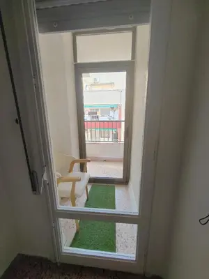 a room with a window with a chair and a green rug at Au bord de la plage in Puerto de Sagunto
