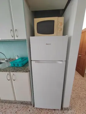 a kitchen with a white refrigerator and a microwave at Au bord de la plage in Puerto de Sagunto