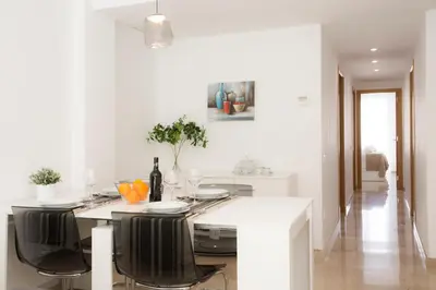 a white kitchen with a table with black chairs at SingularStays Na Jordana in Valencia