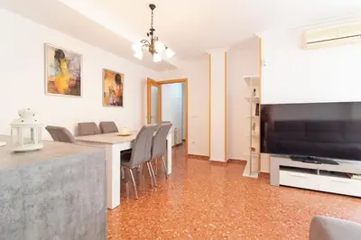 a living room with a table and a large television at Global Vacacional, Apartamento con terraza en la playa de Puerto Sagunto in Puerto de Sagunto