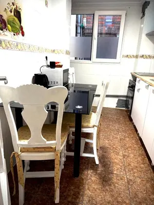 a kitchen with a black table and two white chairs at Habitaciones en Apartamento Port Sagunto in Puerto de Sagunto