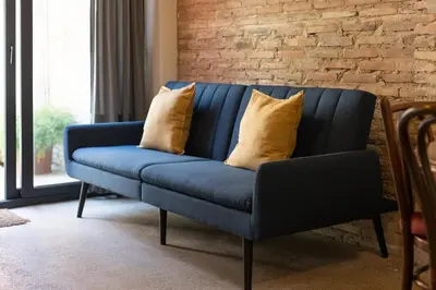 a blue couch with yellow pillows in a living room at Apartamento para 4 huespedes con Patio y ducha Exterior in Valencia