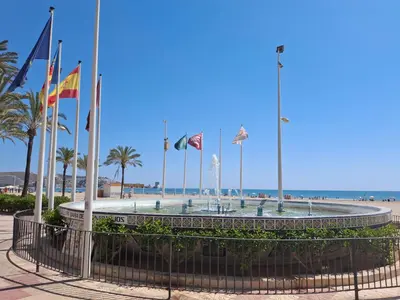 a fountain with flags in front of the beach at Cullera Mar Azul in Cullera
