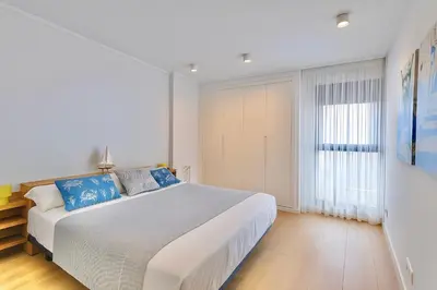 a white bedroom with a large bed with blue pillows at Valencia Beach Home 21 in Valencia