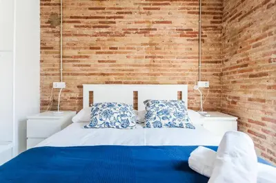 a bed with blue and white pillows and a brick wall at Ruzafa Confort 3 pax wifi Denia 70 in Valencia