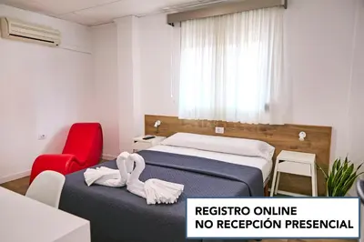 a room with two beds and a red chair at V Pension & Suites in Burriana
