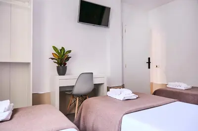 a room with two beds and a desk and a tv at V Pension & Suites in Burriana