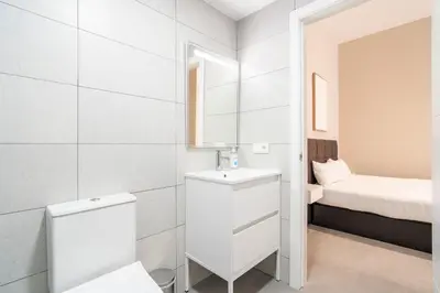 a white bathroom with a toilet and a bed at VLC Host - Sumsi Studios in Valencia