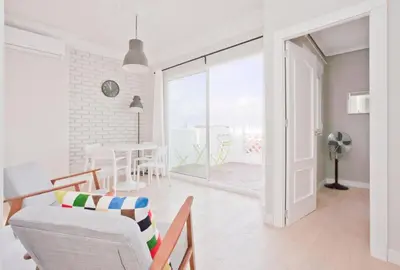a white living room with a chair and a table at El Cabanyal - Mar y Atardecer in Valencia