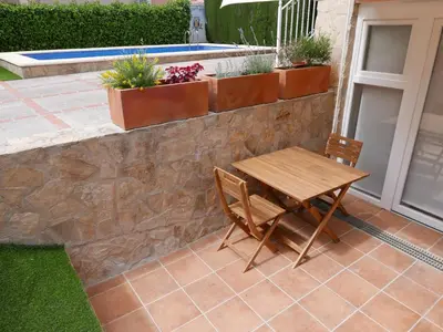 a table and chairs on a patio with plants at Natural park, terrace and pool in Partida de La Cañada