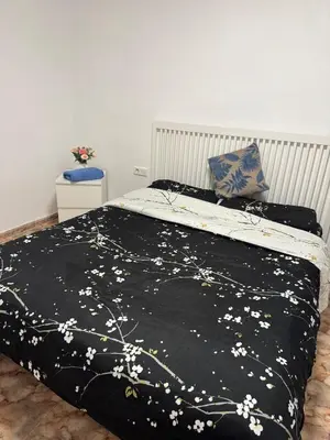 a bed with a black blanket with white flowers on it at Escapate con estilo en Valencia in Valencia