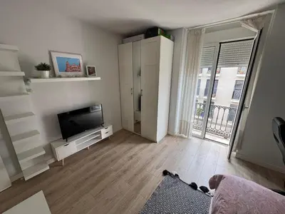 a living room with a tv and a large window at Habitación en el centro con balcón in Valencia